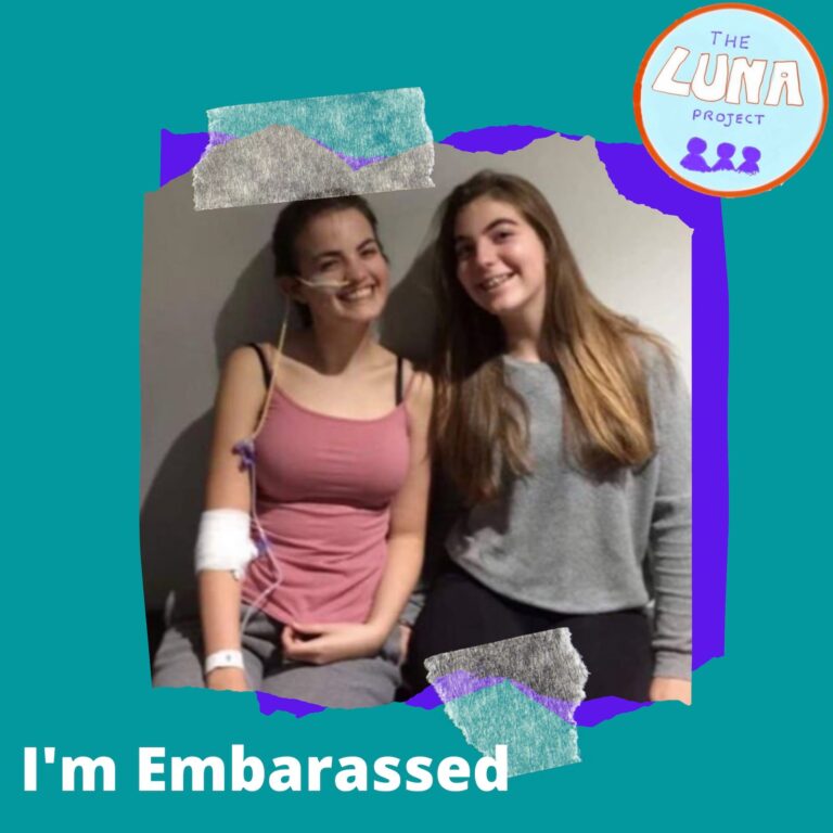 Ella is in hospital and has a bandage on her arm, and a feeding tube. She is sat smiling with her friend Kirsten. This photo is pasted onto a green background and underneath is the text "i'm embarrassed".